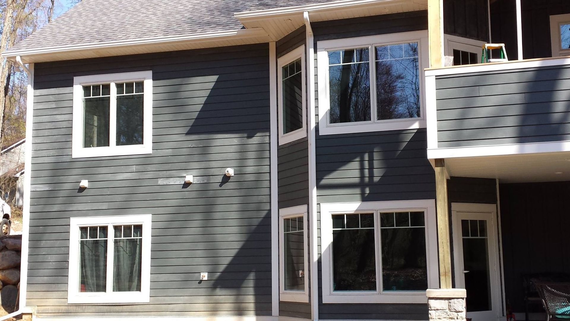 Gray house with white window frames; sunny day.