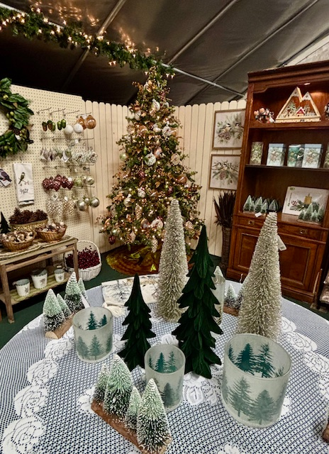 Christmas display: tree, ornaments, decorative tabletop trees, candles, and a bookshelf.