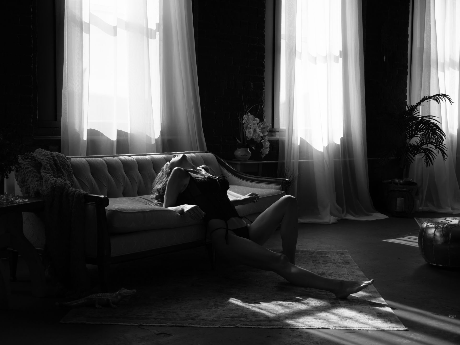 Woman reclining on a couch in a sunlit room, wearing lingerie.