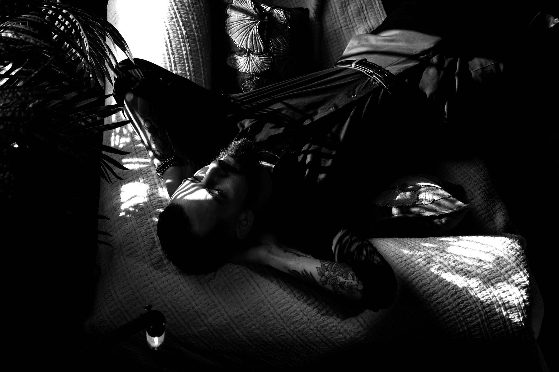 Person lying on a textured surface, possibly a couch. Dark setting with some light highlighting the face and upper body.