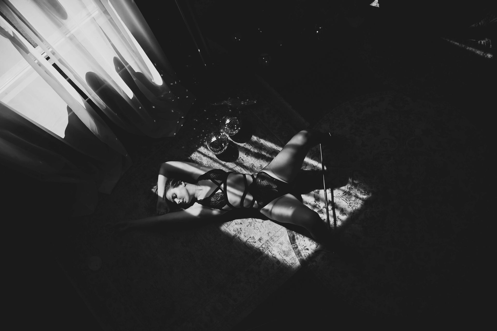 Woman lies on the floor in dappled light, bound with ropes, in a dimly lit room.