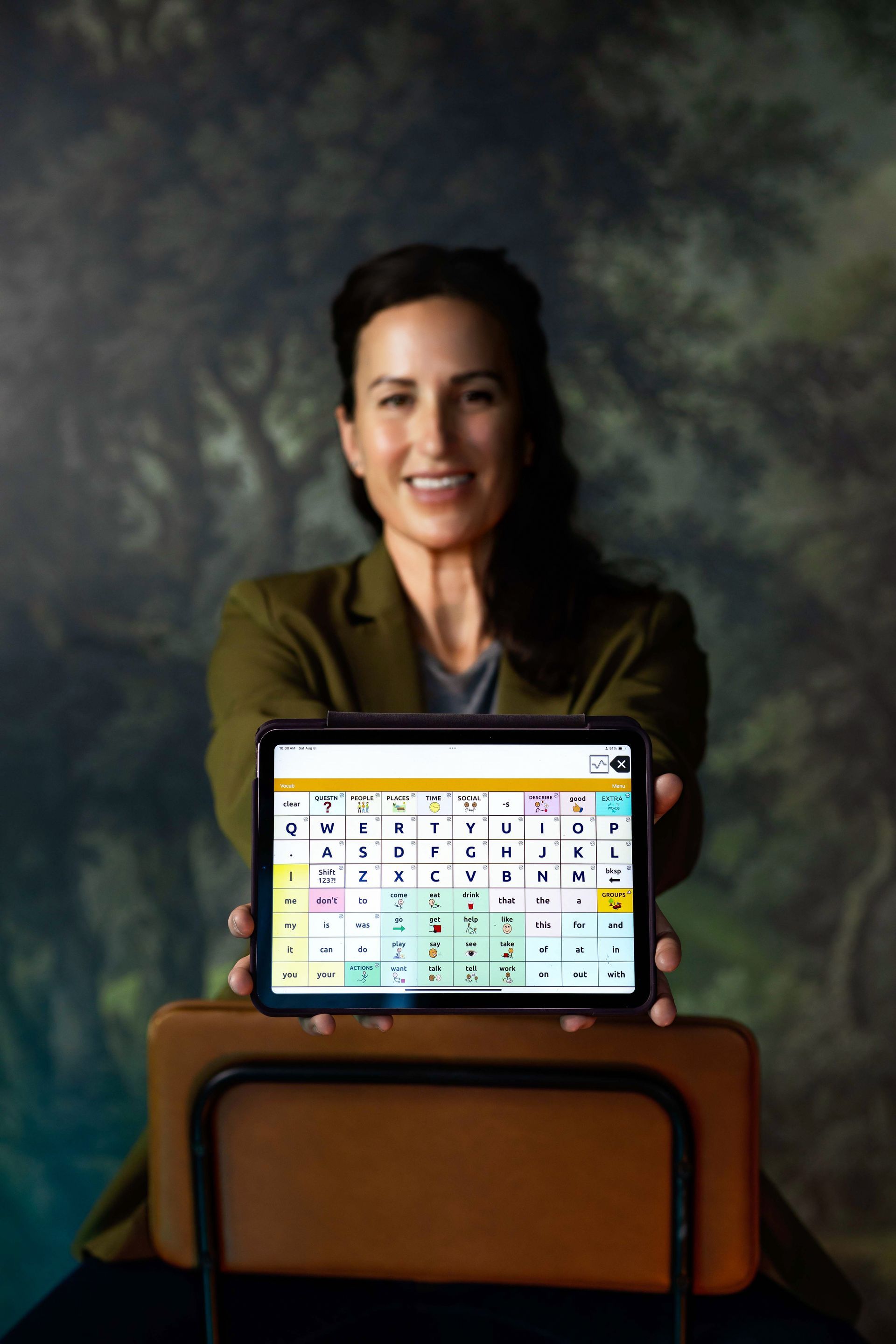 Woman smiling behind a podium with a laptop displaying a colorful calendar on screen