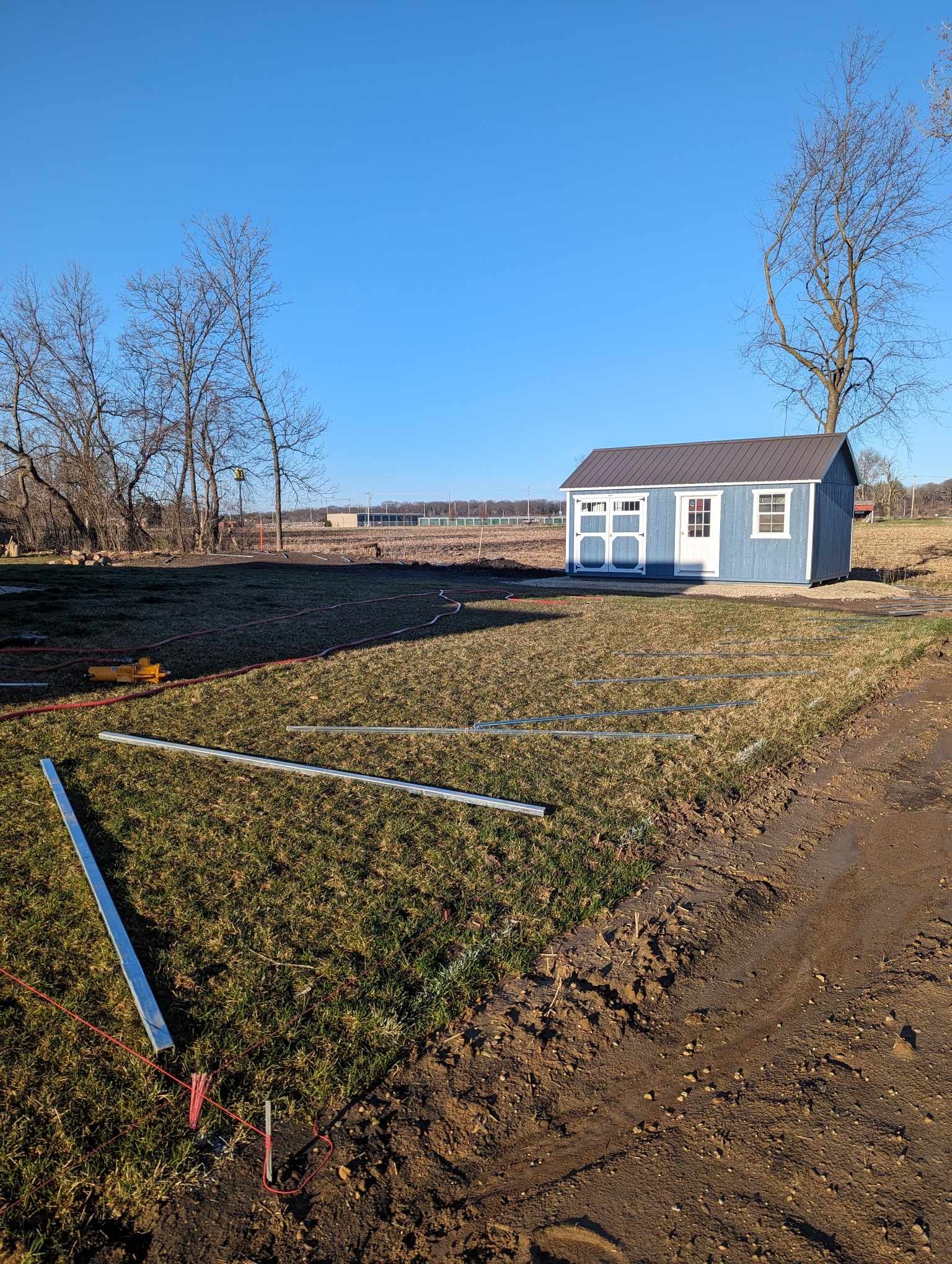 A blue shed is sitting in the middle of a grassy field.