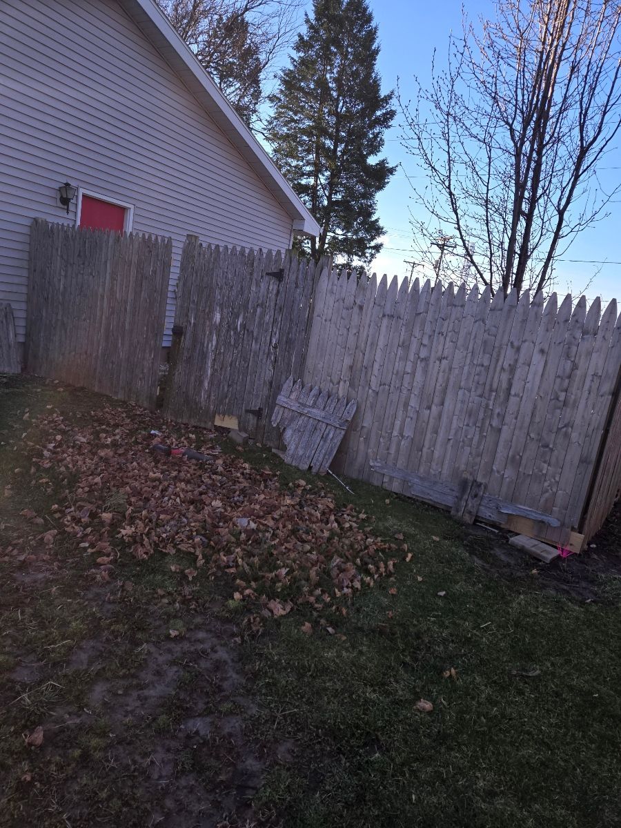 A wooden fence is in the backyard of a house.