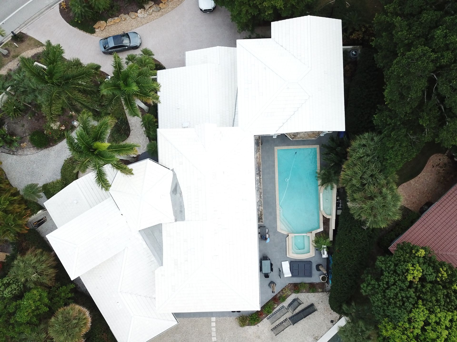 An aerial view of a house with a pool and a car parked in front of it.