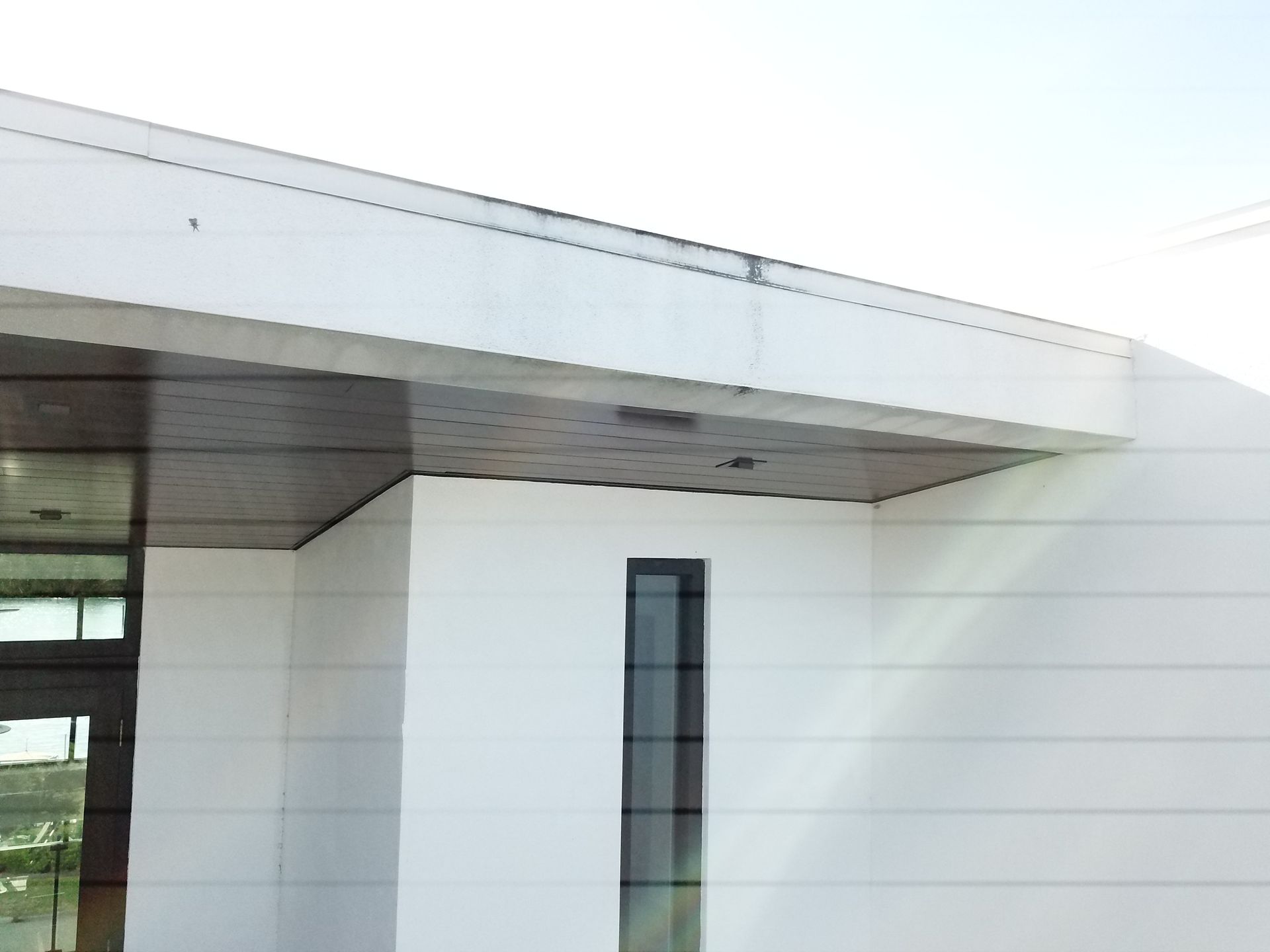 A white building with a black door and a roof