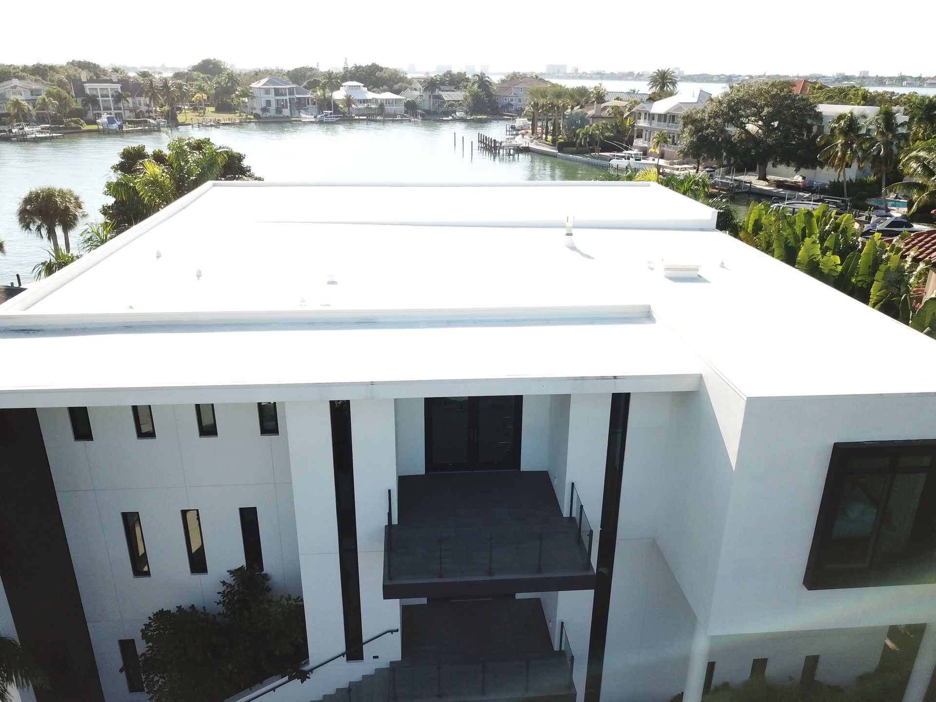 An aerial view of a large white house with a white roof