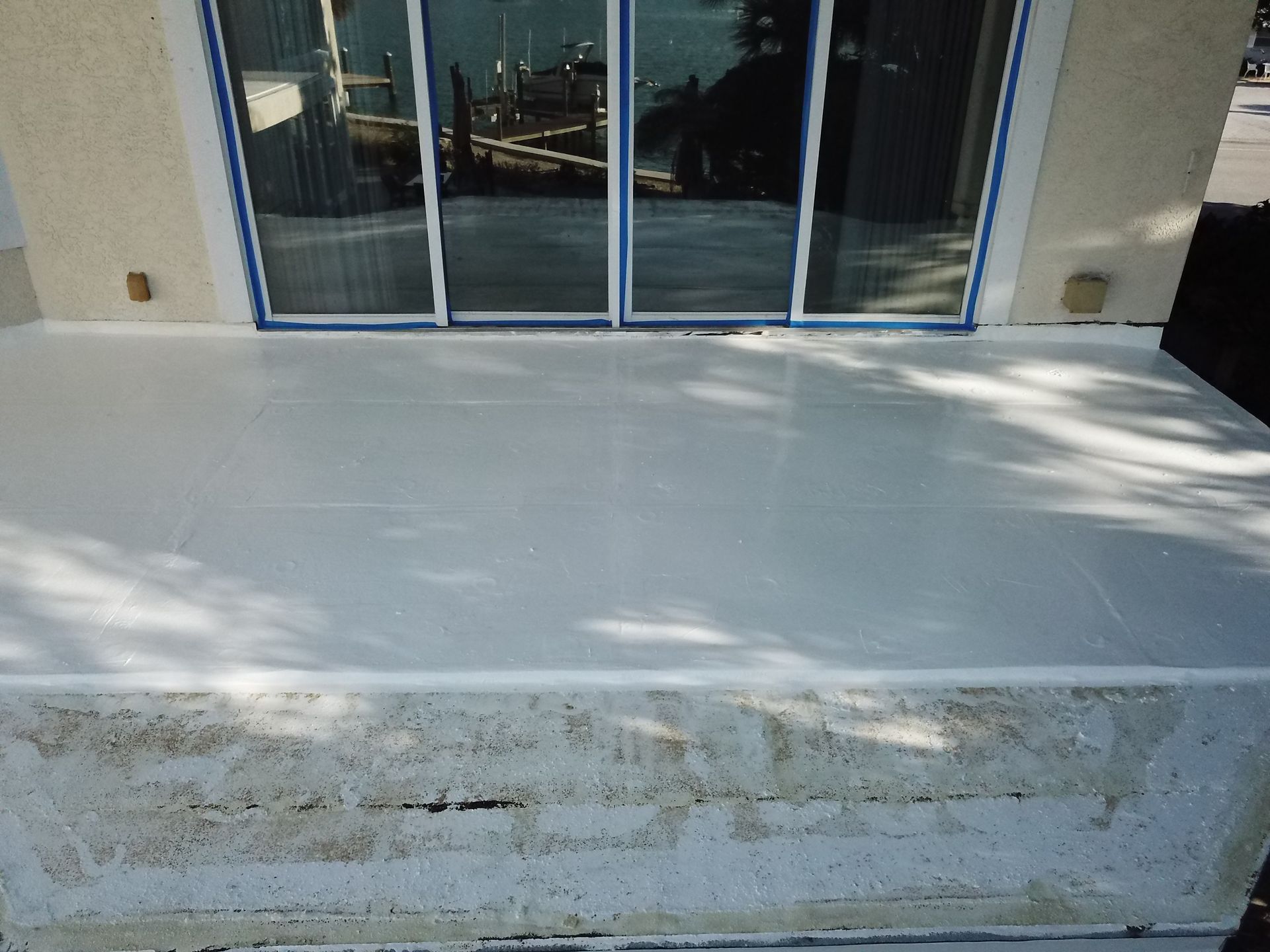 A white deck with a sliding glass door in the background