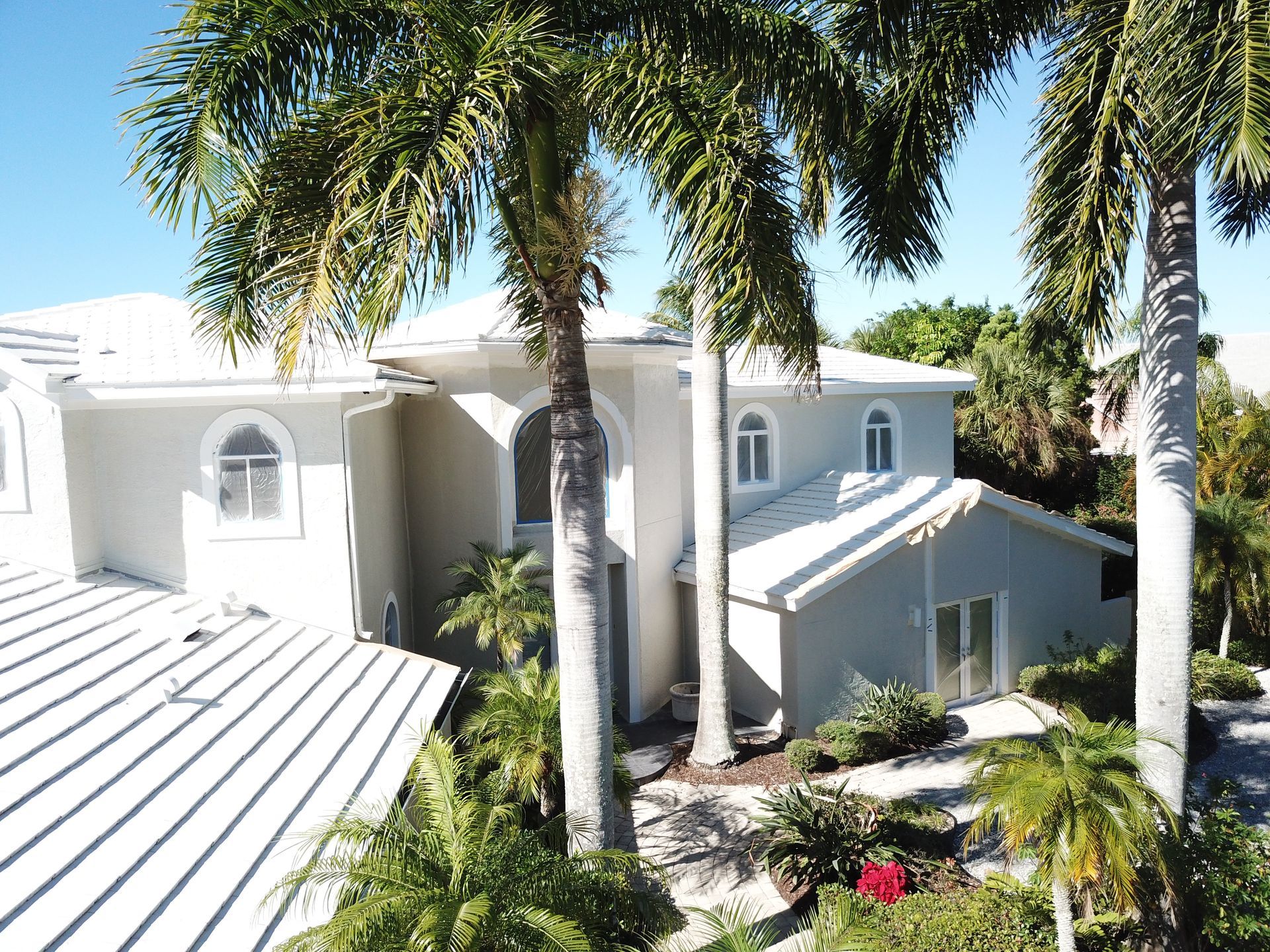 An aerial view of a large white house surrounded by palm trees