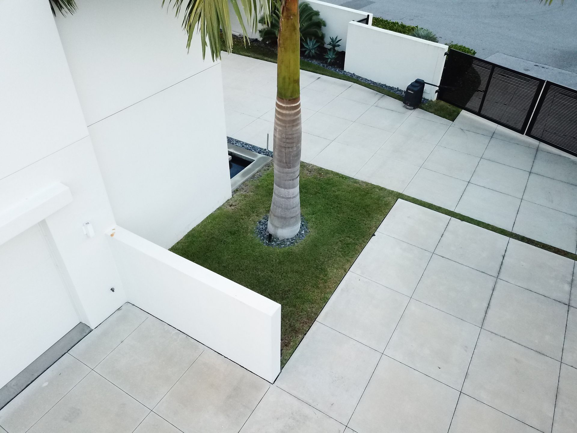 An aerial view of a driveway with a palm tree in the middle