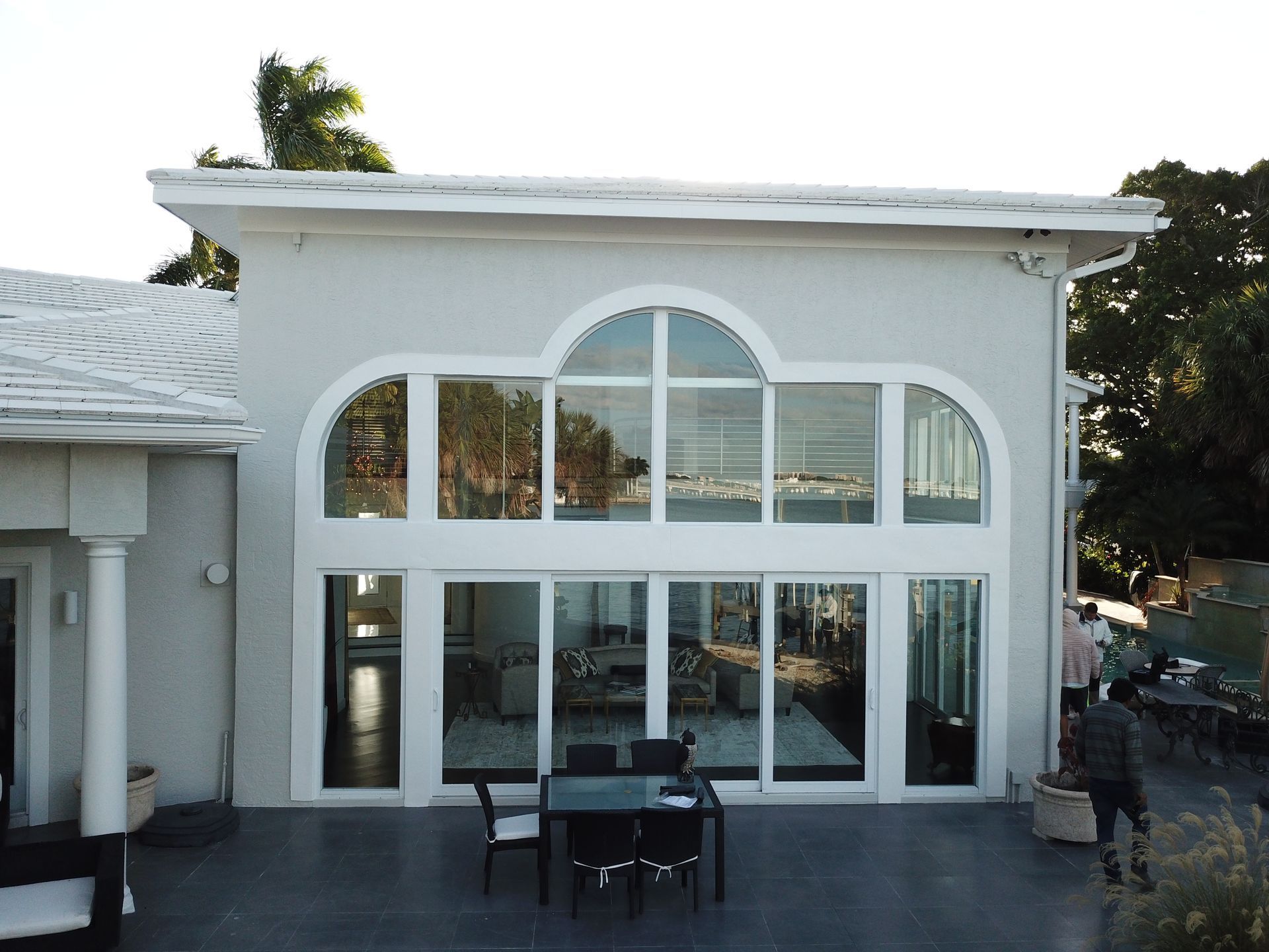 A large white house with a lot of windows and a table and chairs on the patio.