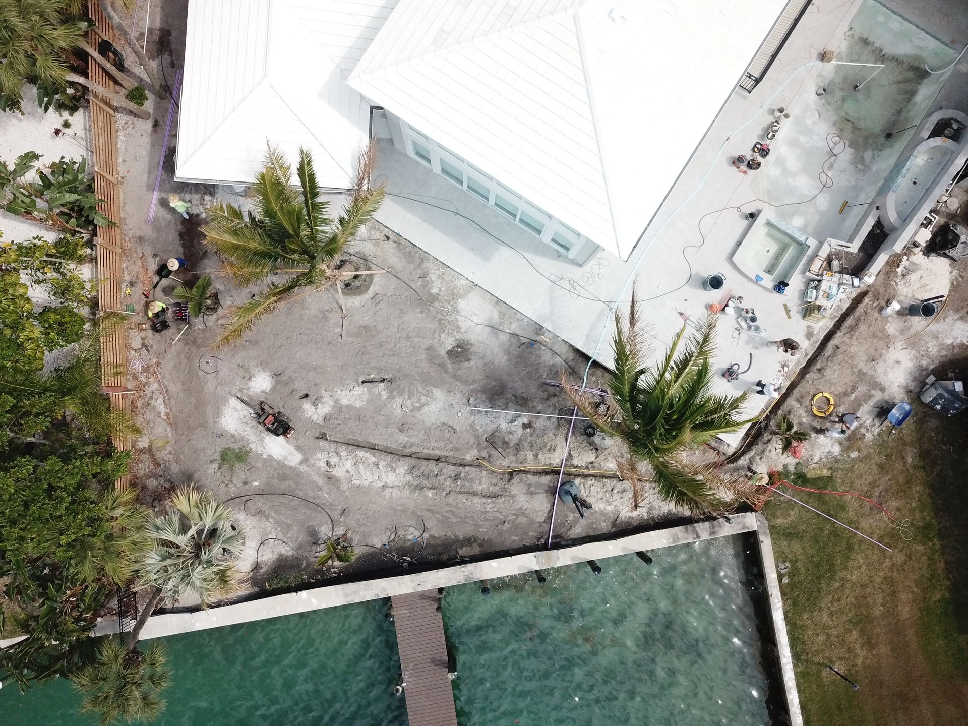 An aerial view of a house under construction with a pool and palm trees.