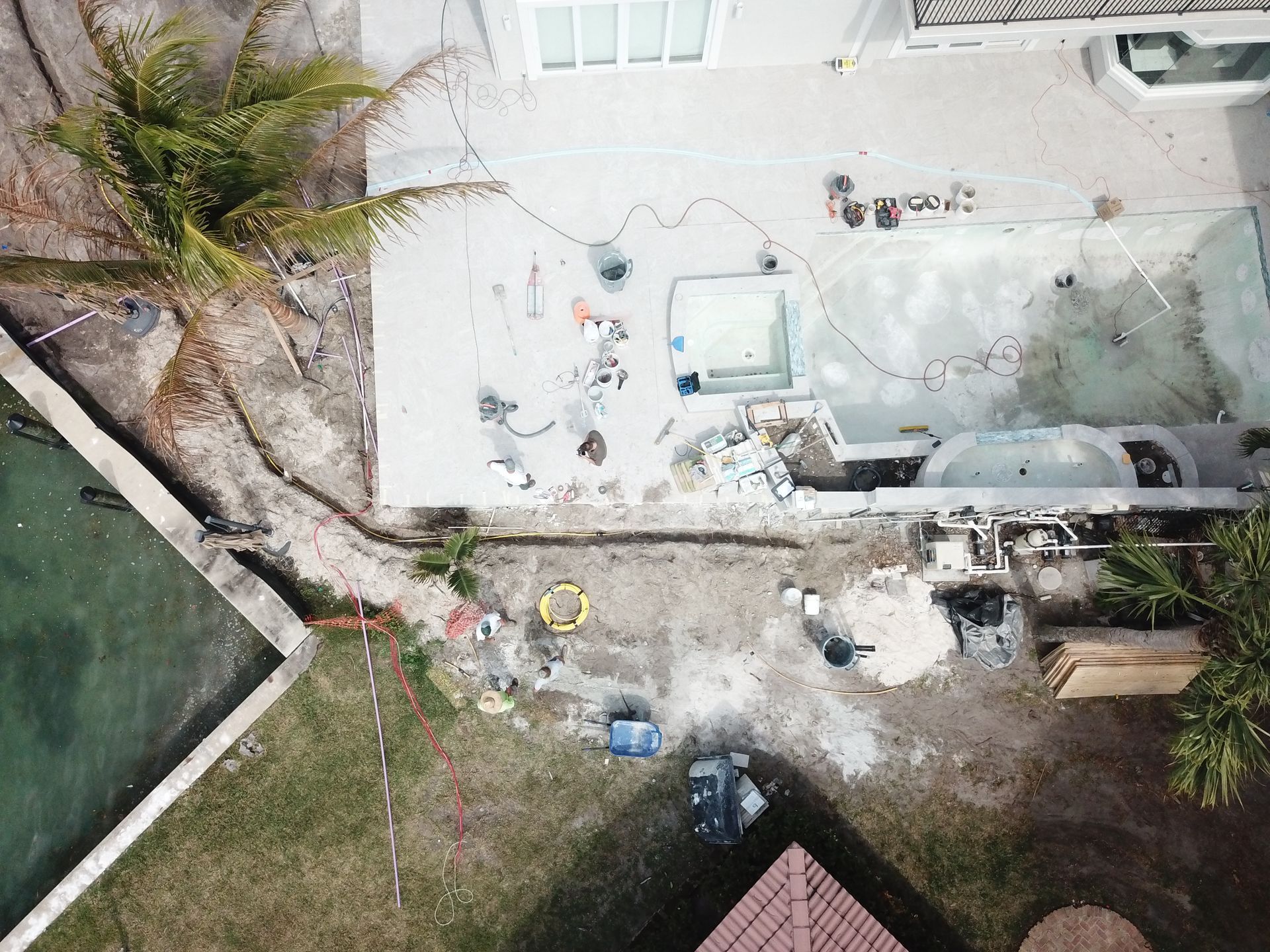 An aerial view of a house under construction with a pool in the background.