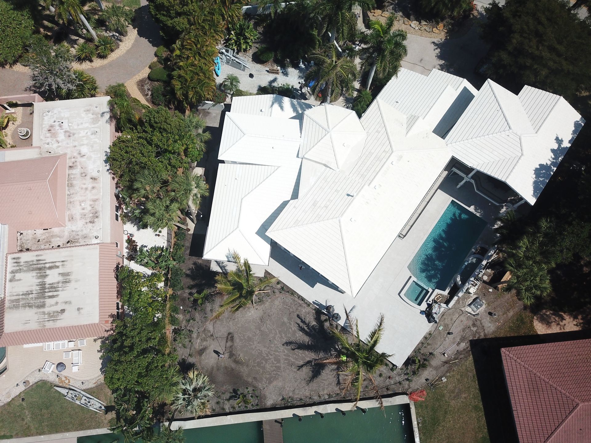 An aerial view of a house with white roofs and a pool