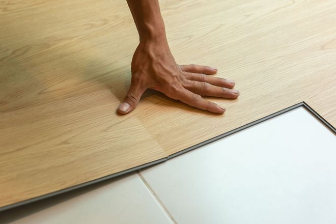 Man stands in a flooring showroom, surrounded by tile and carpet samples. Sale sign visible.