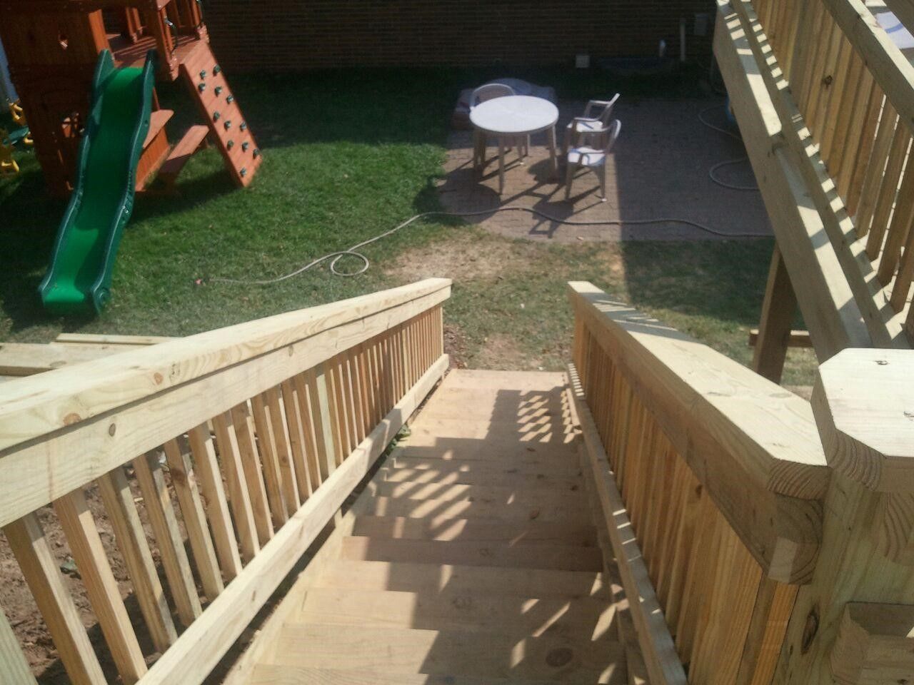 A wooden deck with stairs and a slide in the background