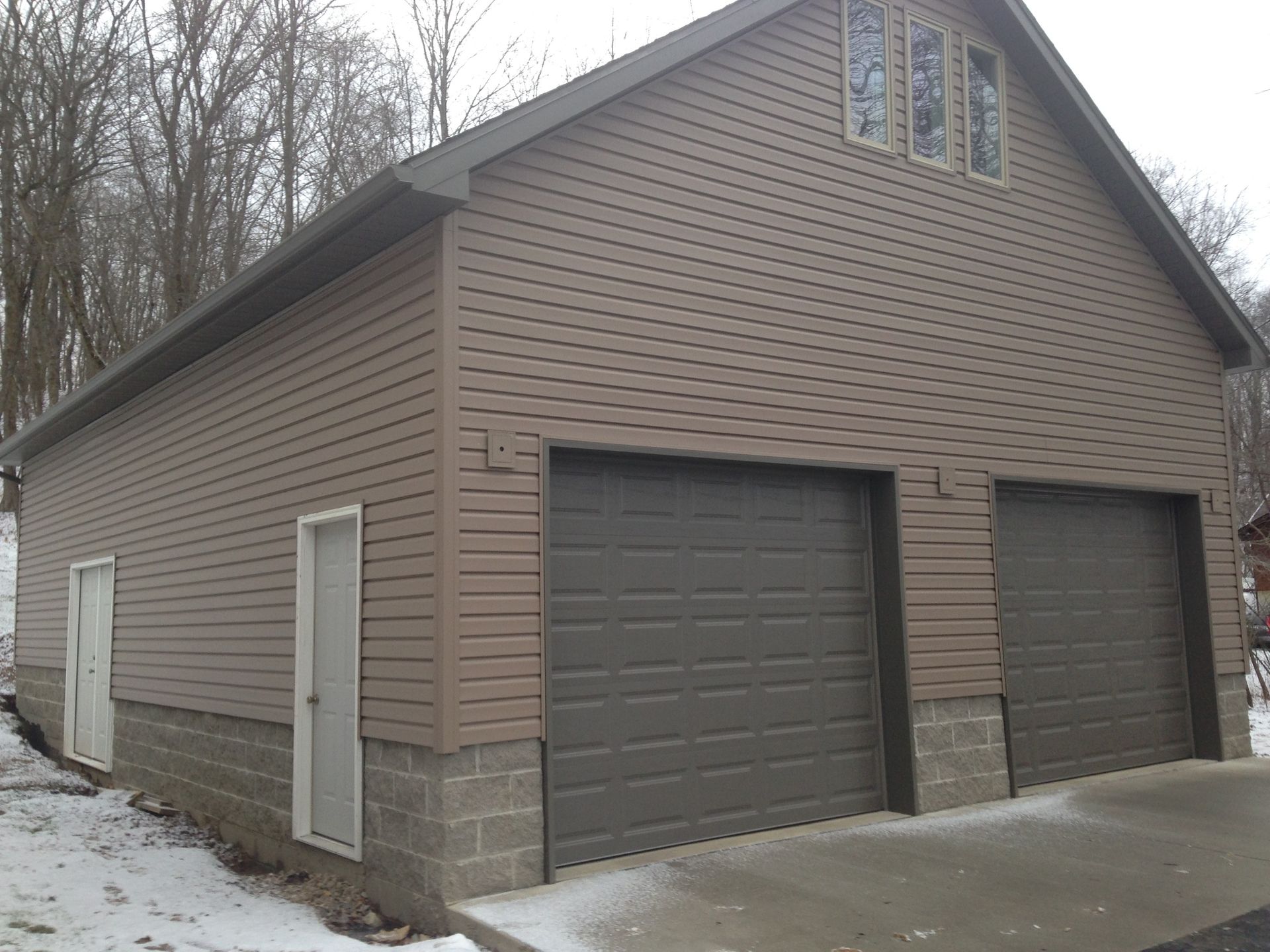 A large garage with three garage doors and a roof
