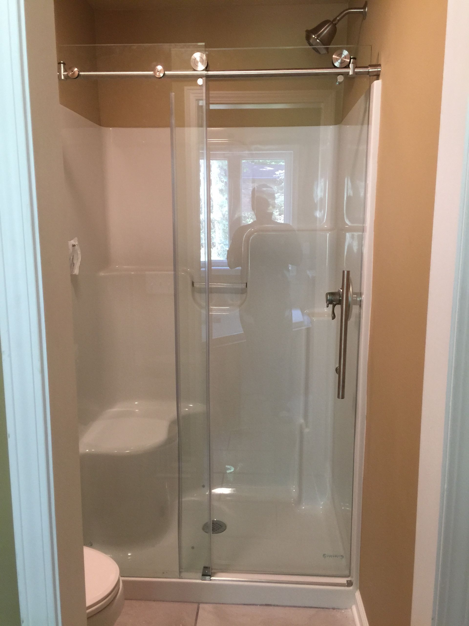 A bathroom with a sliding glass shower door and a toilet.