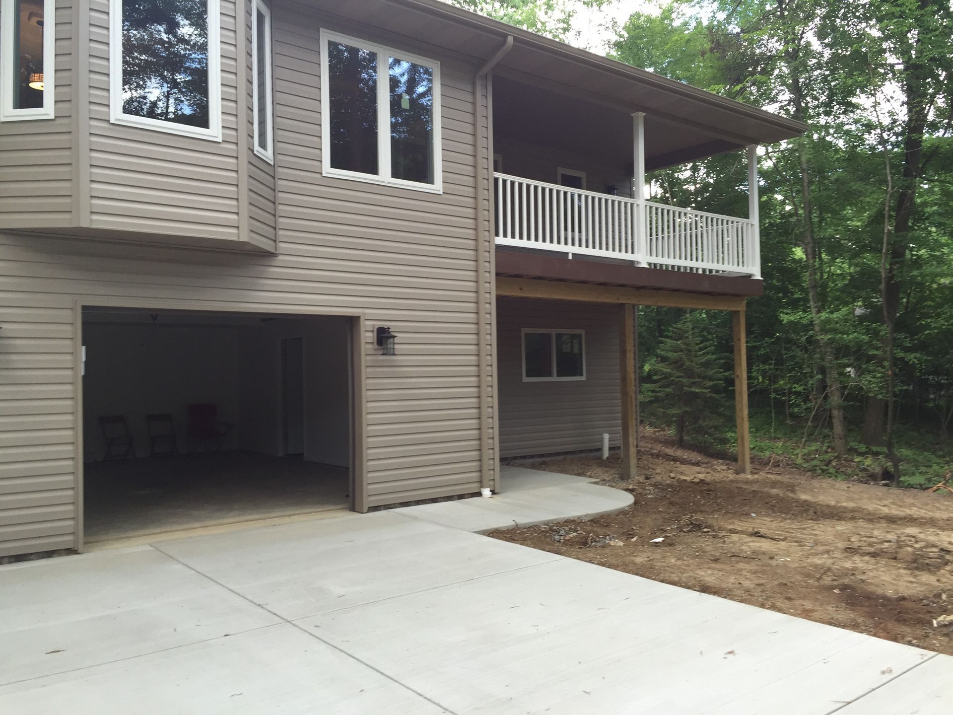 A house with a garage and a porch in the woods
