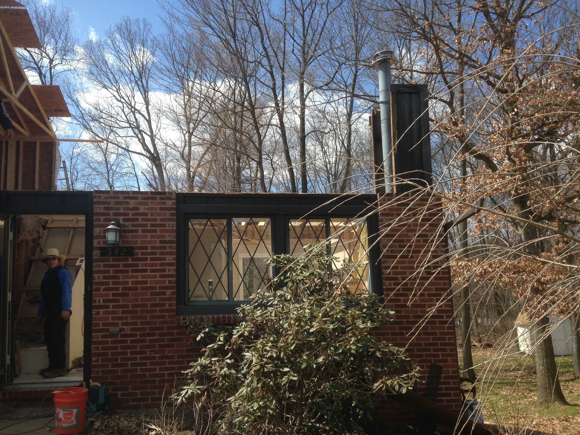 A man is standing in front of a brick house.