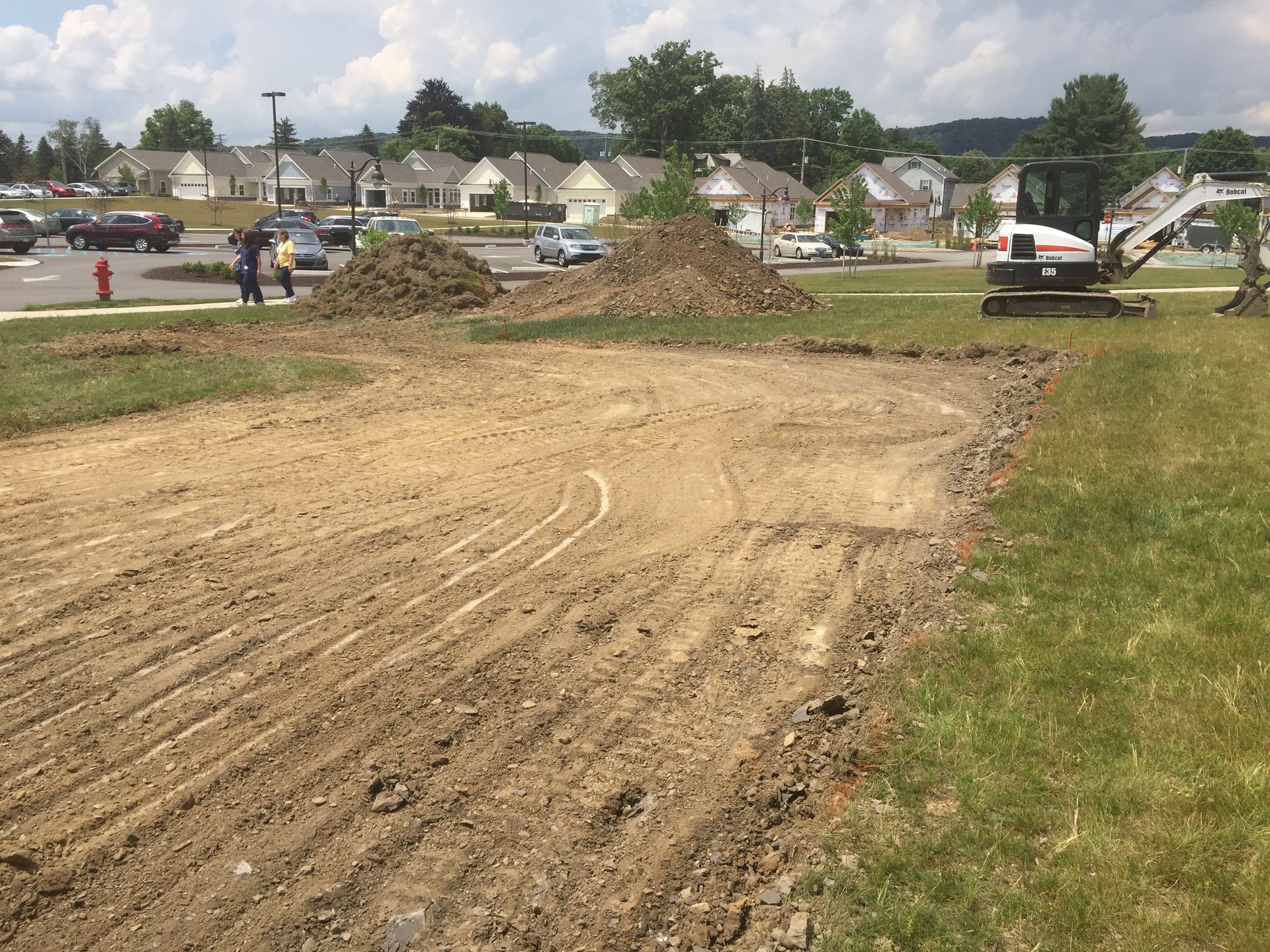 A bulldozer is working on a dirt field in a residential area