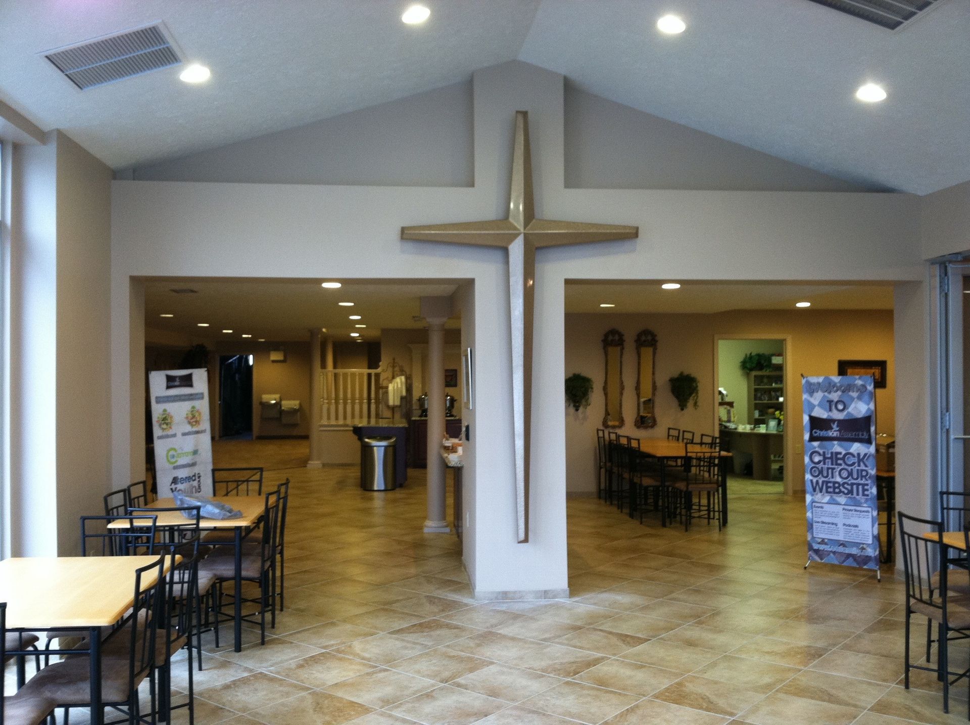 A room with tables and chairs and a cross on the wall