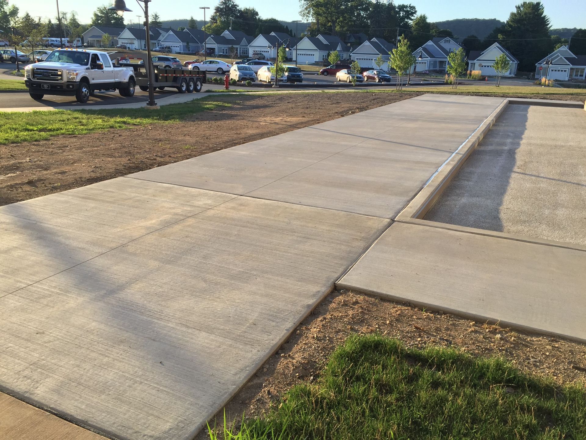 A white truck is parked on the side of a concrete walkway
