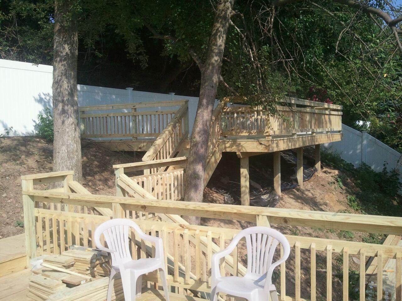 A wooden deck with two white chairs on it
