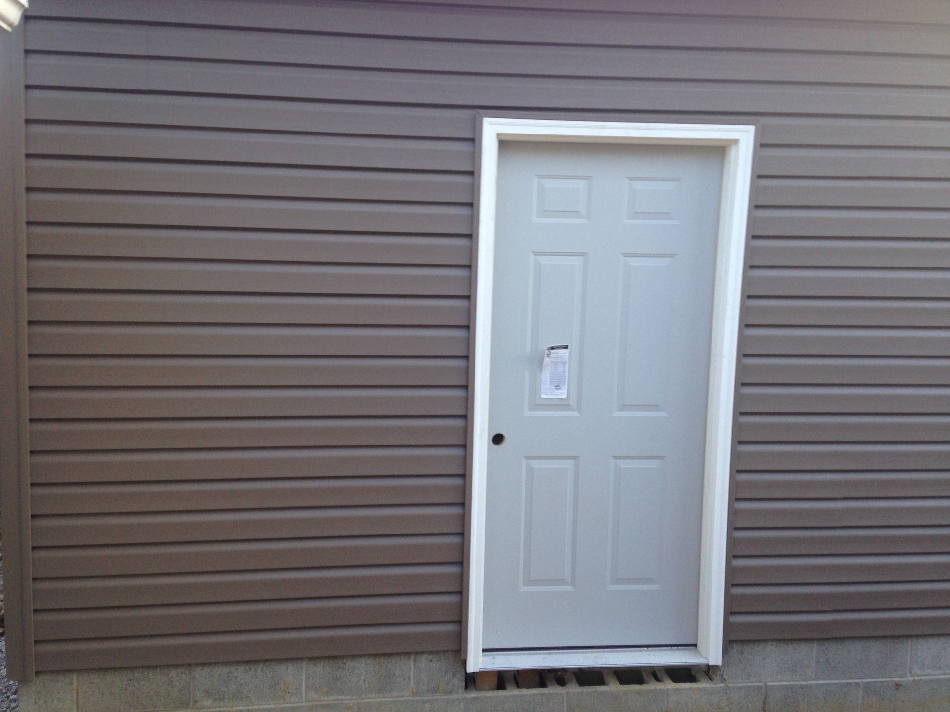 A white door is on the side of a brown building.