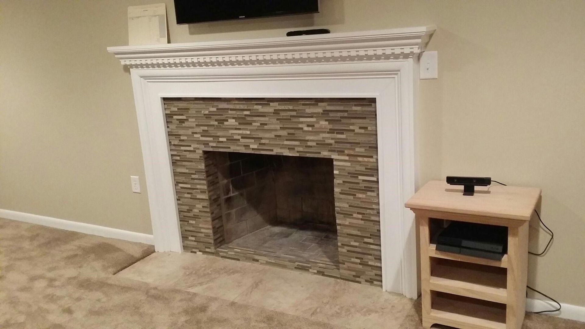A living room with a fireplace and a television on the wall.