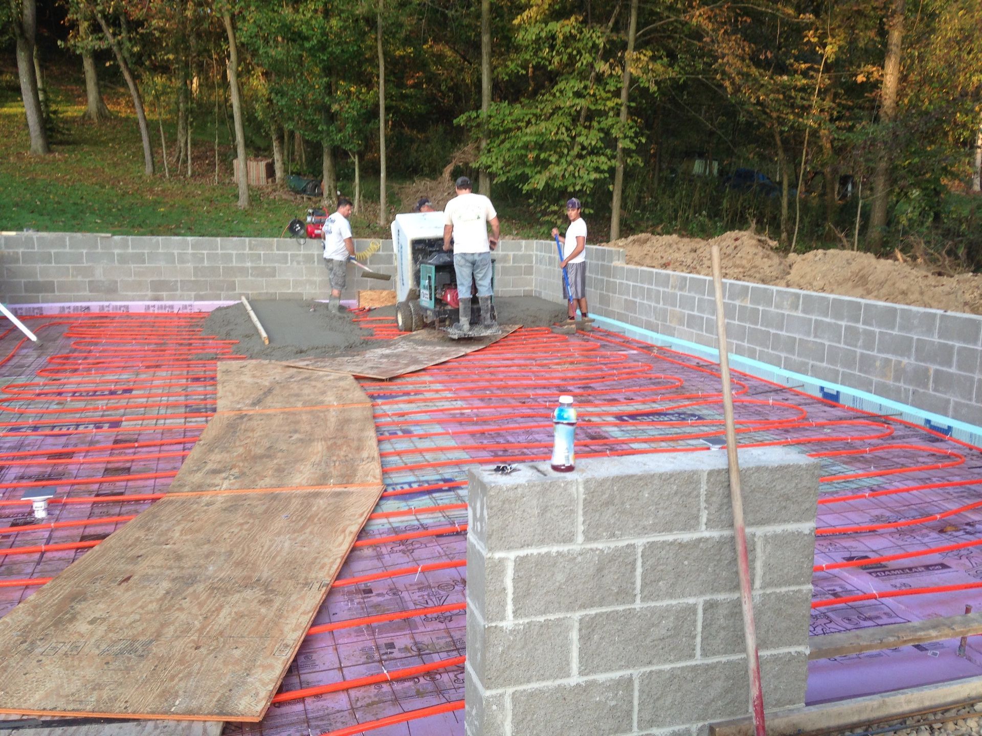 A group of men are working on a foundation of a house.