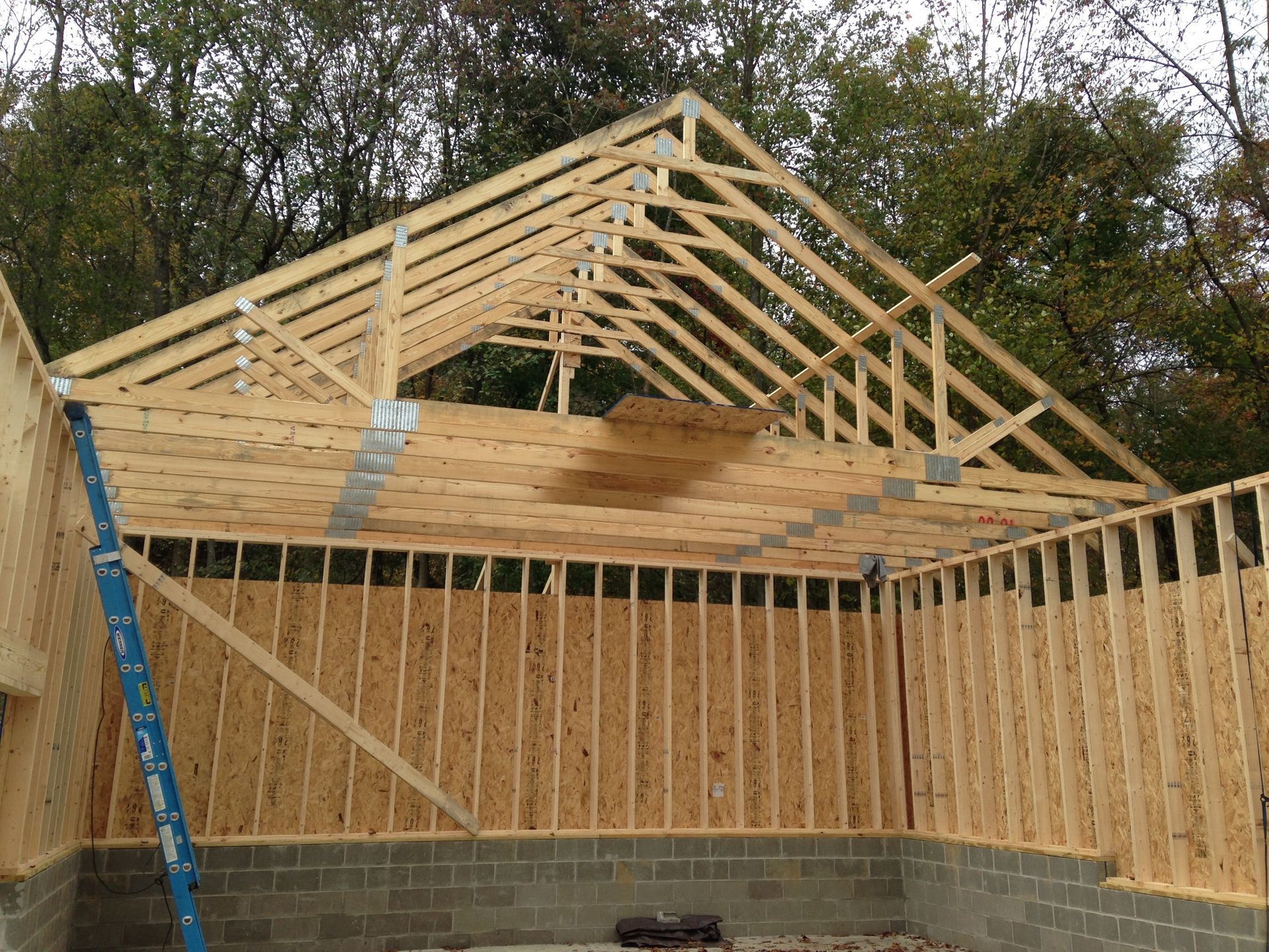 A wooden structure is being built with a blue ladder in the foreground.