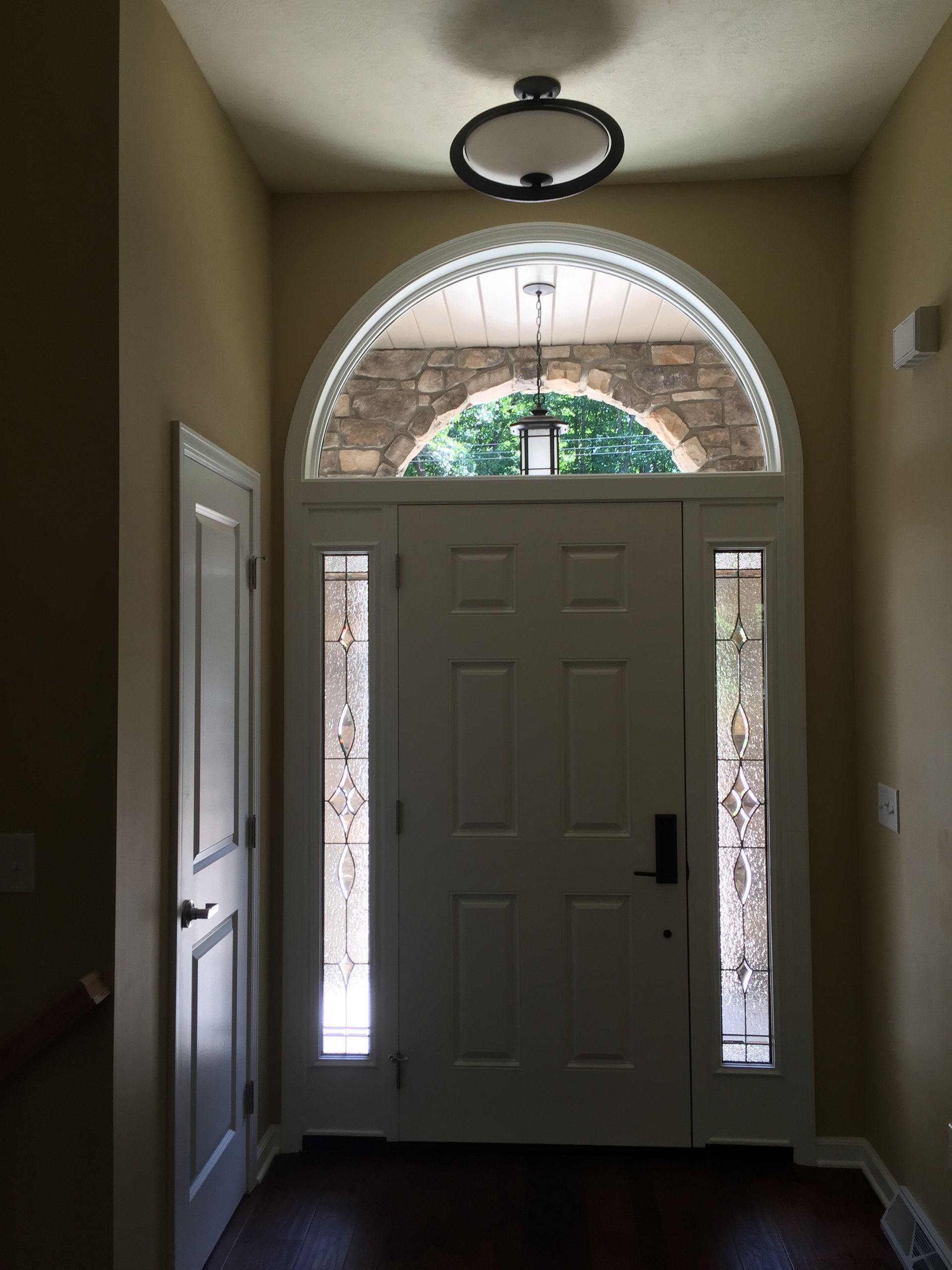 A white door with a stone arch and stained glass windows