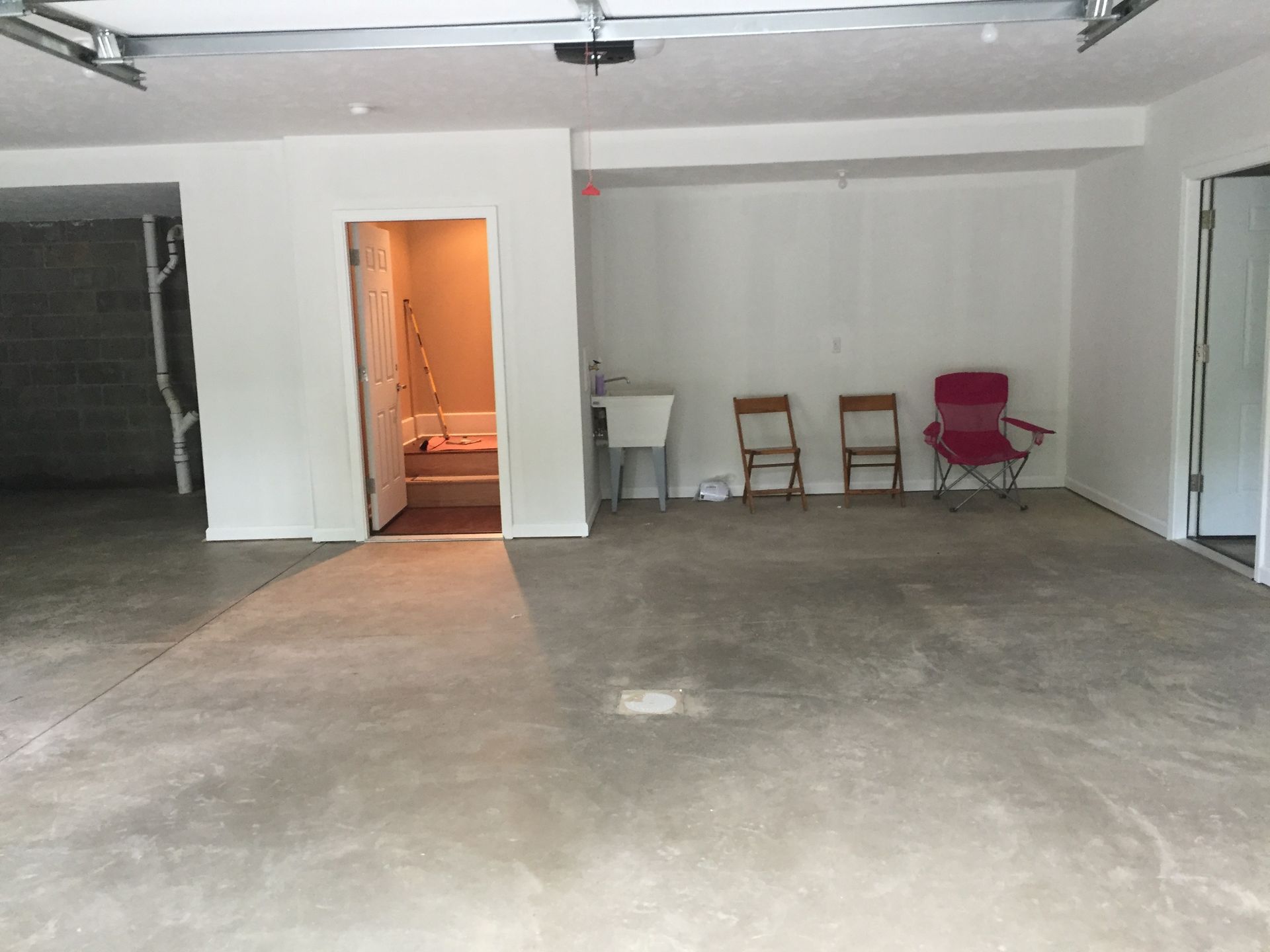 An empty garage with a sink and chairs in it.
