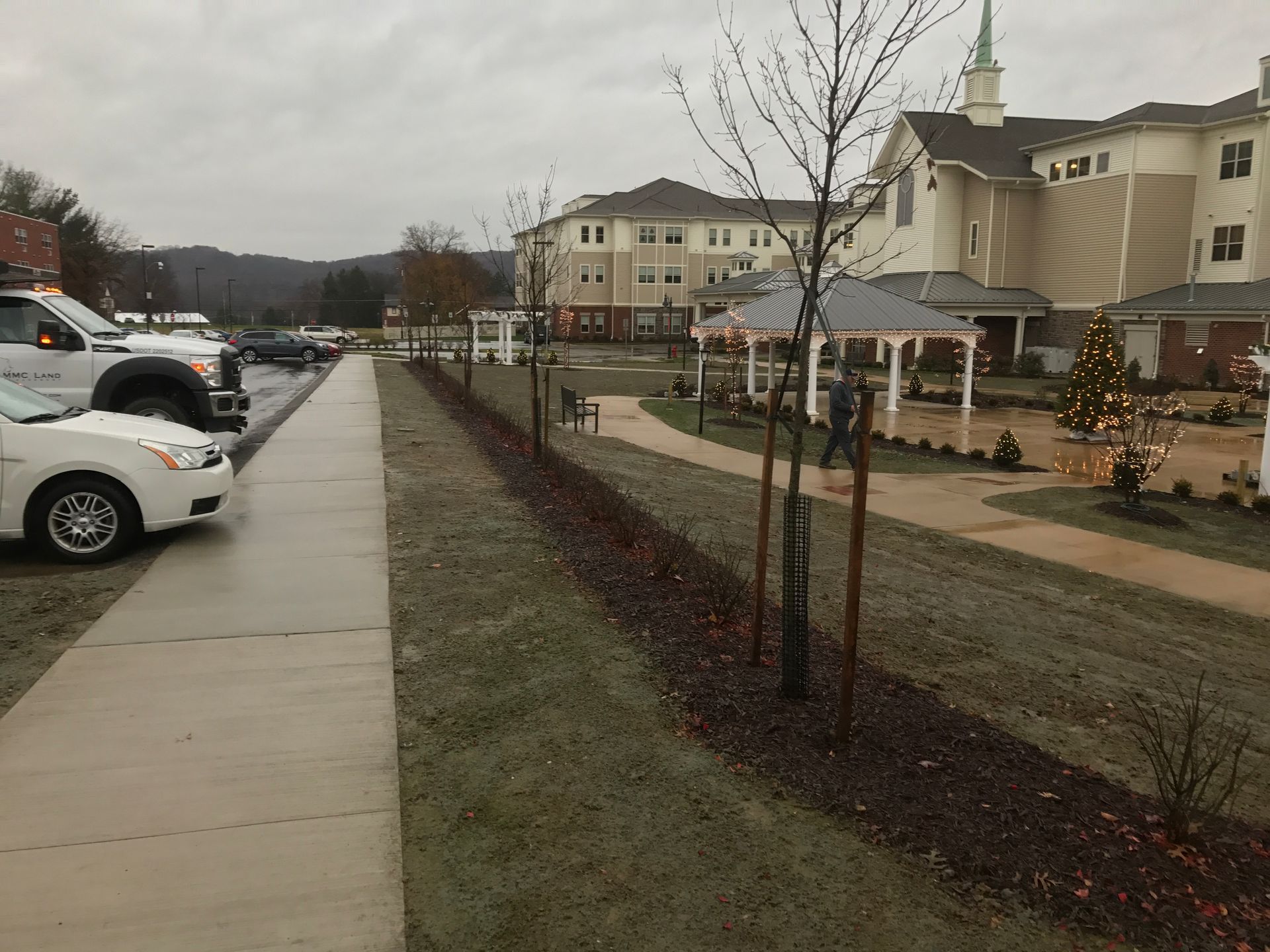A white car is parked on the sidewalk in front of a church