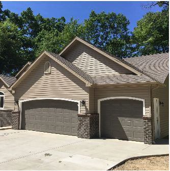 Tan house with two garage doors and a concrete driveway.