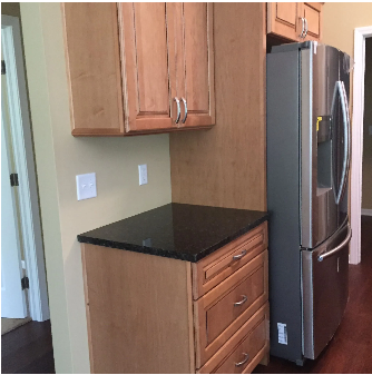 Kitchen corner with cabinets, countertop, drawers, and stainless steel refrigerator.