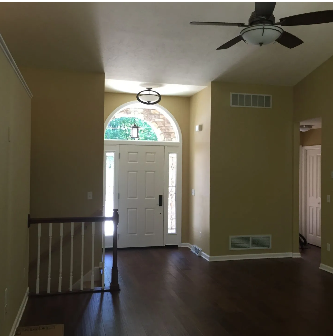 Entryway with dark wood floor, tan walls, and a white door with arched window.