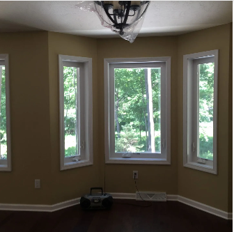 Interior room with three windows, a dark floor, and beige walls.