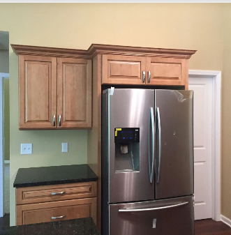 Kitchen with stainless steel refrigerator and light wood cabinets.