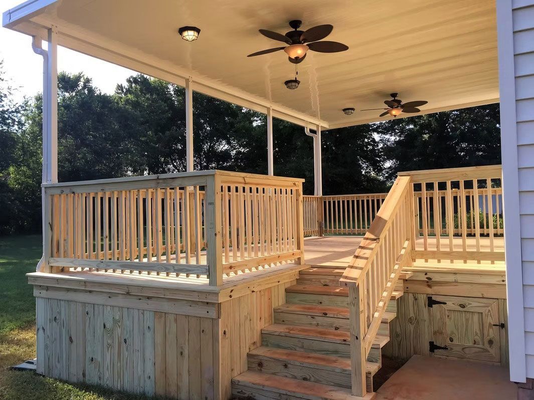 Wooden deck with stairs, railings, and a covered patio featuring ceiling fans, situated in a backyard.