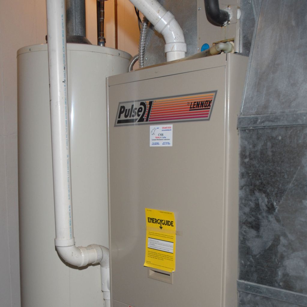 Furnace and water heater in a utility room. Beige appliances and silver ductwork.
