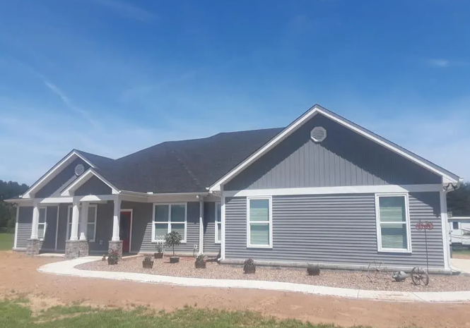 Single-story gray house with white trim and a front porch under a blue sky