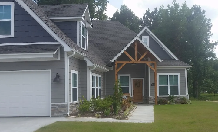 Gray house exterior with white trim, garage, and covered front porch with wood accents