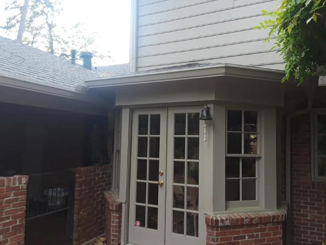 Brick house entry with white French doors, windows, and a small covered porch