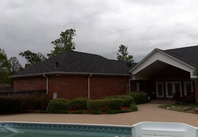 Brick building with dark roof beside a pool under a cloudy sky