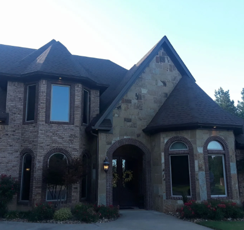 Large brick and stone house with arched windows and a steep dark roof in daylight
