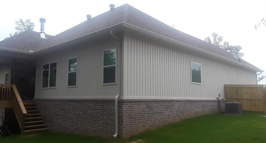 Single-story house with beige siding, brick foundation, and a small wooden staircase on the left.