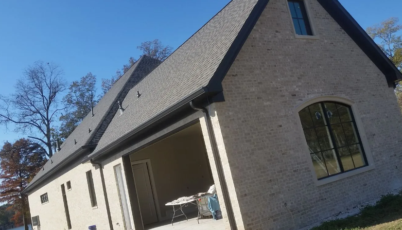 New brick house with a steep roof and covered porch on a sunny day