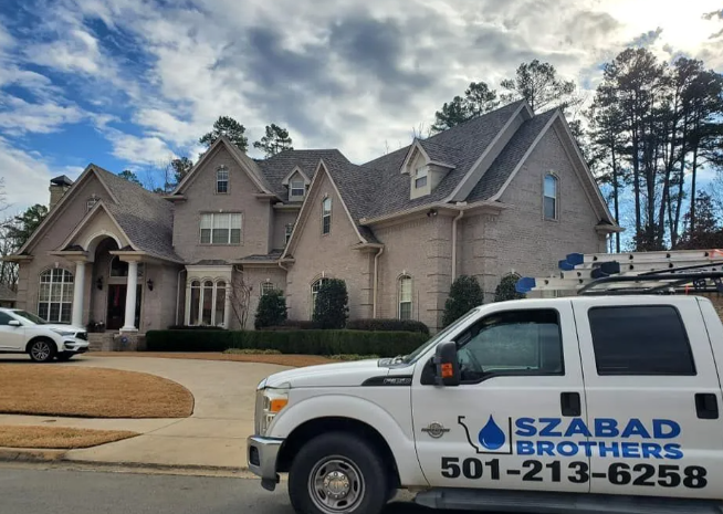 Brick house with a white Szabad Brothers service truck parked in front under a cloudy sky